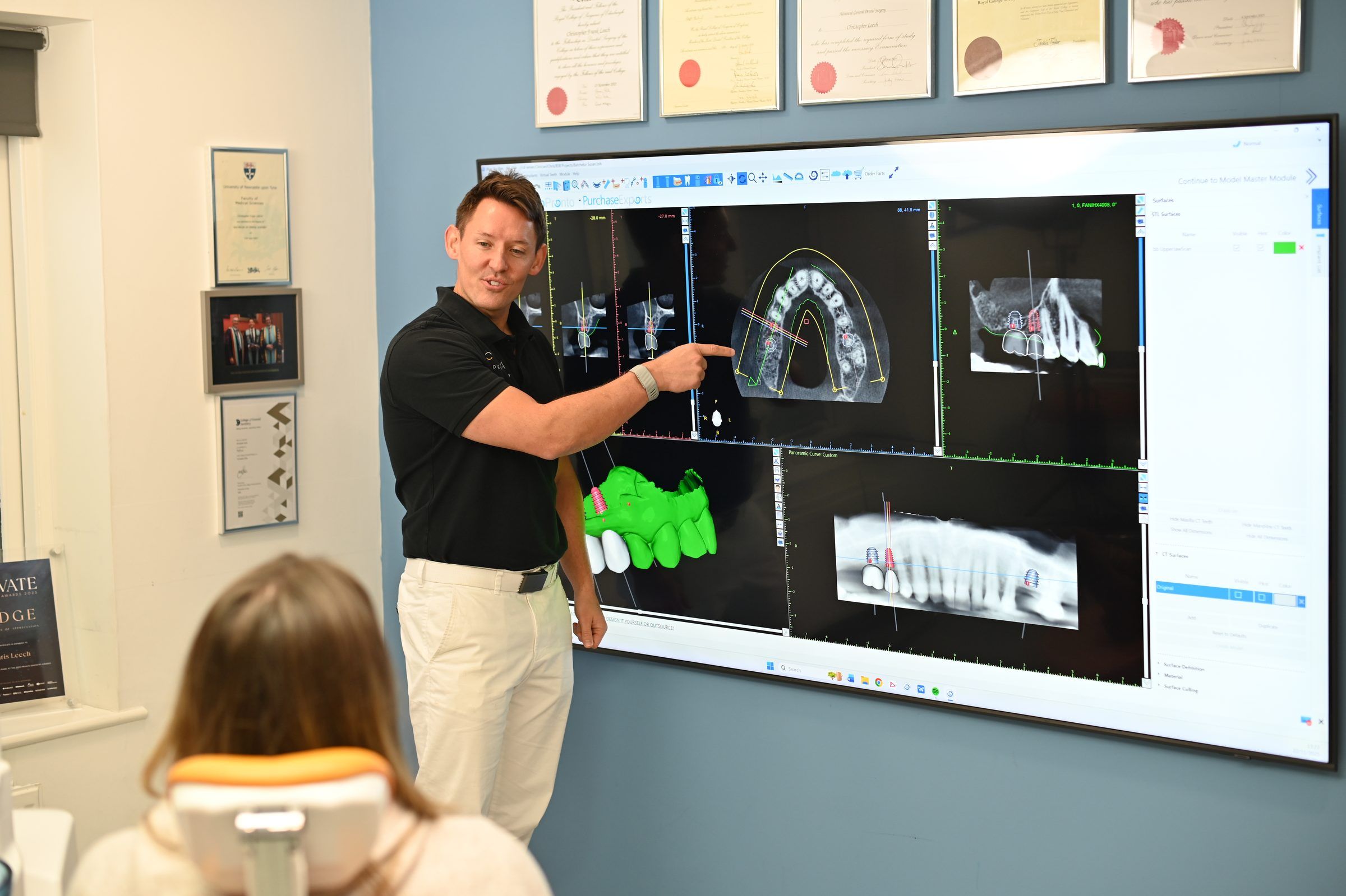 Dr Chris Leech showing a patient her 3D CBCT implant plan on the wall screen